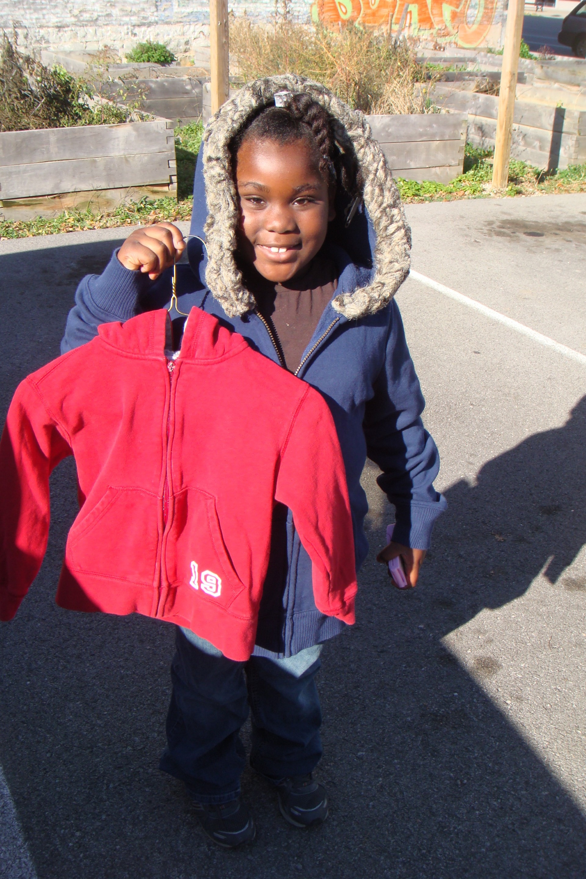 A child holding a red jacket received from Free Coat Exchange